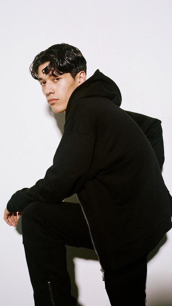 Male model wearing an oversized black hoodie